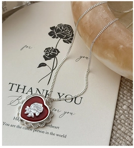 Close-up of S925 silver heart necklace with red cameo rose inlay and ornate filigree edge
