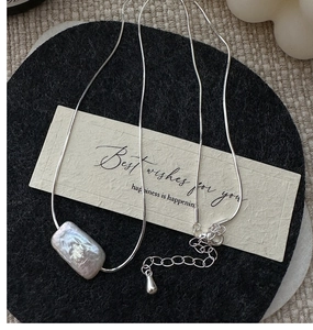 Macro detail of a rectangular baroque pearl pendant on a silver snake chain necklace