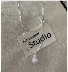 Macro shot of silver double-layered necklace featuring a matte finish gourd pendant
