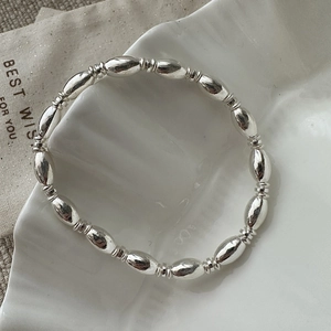 Minimalist S925 sterling silver beaded bracelet on a white textured ceramic plate