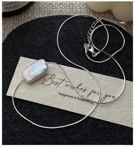 Macro shot of silver S925 sterling silver chain with a baroque rectangle pearl pendant