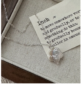 Vue détaillée du collier fleur en argent S925 avec perle baroque sur fond vintage chic