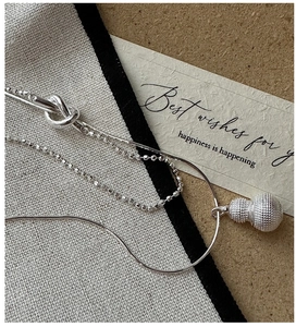Macro detail of silver double-layered S925 necklace featuring a textured gourd pendant