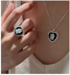 Detail of vintage heart-shaped cameo ring and necklace set with white rose floral relief