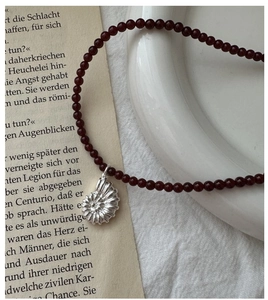 Detail of S925 silver ammonite pendant with deep red carnelian beads on vintage book pages