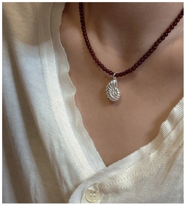 Detailed view of silver nautilus shell pendant on a red agate bead chain necklace