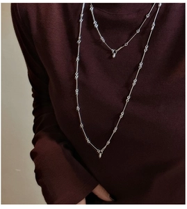 Detail of layered S925 sterling silver bamboo link necklaces on a dark turtleneck sweater