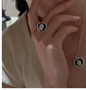 Close-up of vintage heart cameo ring and necklace with white rose relief detail
