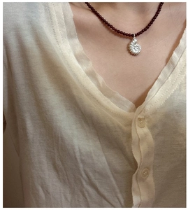Detail of S925 silver ammonite pendant on red agate beaded necklace worn by model