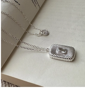 Detailed view of S925 silver square zircon necklace lying on vintage book pages