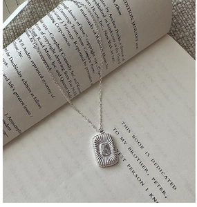 Macro shot of S925 sterling silver necklace with square zircon on an open book