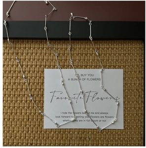 Detail of S925 sterling silver bamboo link necklace on a textured woven mat background