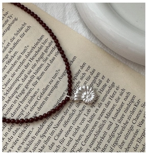 Macro detail of S925 silver ammonite shell pendant with red agate beads on a vintage book