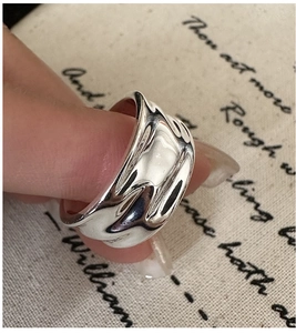Macro detail of silver liquid metal ring featuring organic lava texture and polished finish
