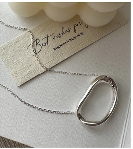 Detailed macro of a silver S925 oval pendant necklace with a liquid metal mirror finish