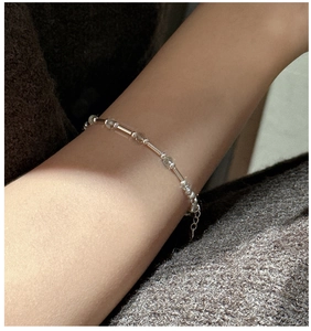 Detail of minimalist S925 sterling silver beaded bracelet on wrist with adjustable chain