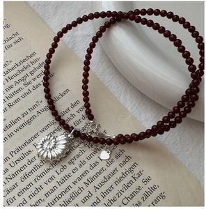 Macro shot of red agate beaded necklace with silver ammonite shell charm on vintage book