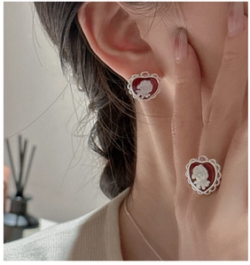 Close-up of red cameo rose earrings and ring set in silver heart lace frames