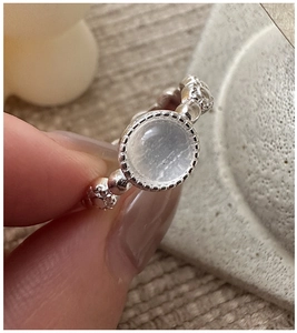 Detail of S925 silver ring featuring a round moonstone and beaded texture band on finger