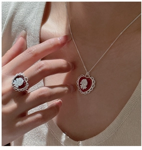 Dettaglio di collana e anello in argento S925 con cuore cammeo rosso e rosa bianca