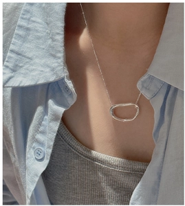Detail of silver S925 necklace featuring an irregular hollow oval pendant on a model