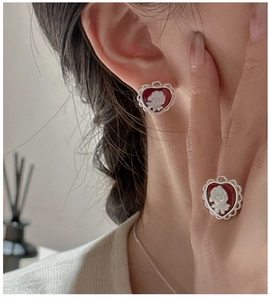 Macro detail of S925 silver heart cameo earrings and ring set with red floral relief