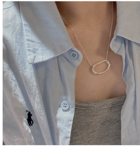 Detail of S925 sterling silver minimalist necklace with irregular oval pendant on neck