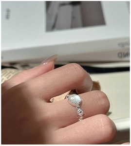 Detailed view of an S925 silver beaded ring with an oval pale green gemstone on a finger