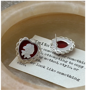 Macro view of S925 sterling silver heart earrings with red rose cameo relief detail