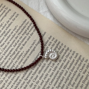 S925 sterling silver shell pendant necklace with red agate beads on a vintage book