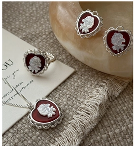 Macro detail of S925 silver heart cameo jewelry set with red enamel and white rose relief