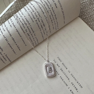 Vintage S925 silver square zircon necklace displayed on an open book at a 45-degree angle
