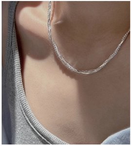 Gros plan d'un collier tressé en argent sterling S925 porté sur le cou d'une femme