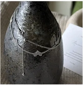Detailed view of silver double-layered heart necklace on a textured black vase