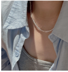 Détail d'un collier multicouche en argent sterling S925 sur une chemise bleue