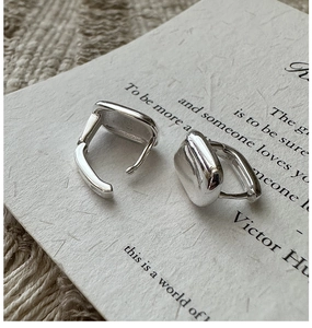 Vue macro des boucles d'oreilles carrées en argent S925 avec texture métallique polie