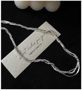 Gros plan d'un collier en argent sterling S925 à chaînes torsadées sur fond noir
