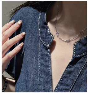 Detail of silver S925 heart pendant necklace worn on a model with denim outfit