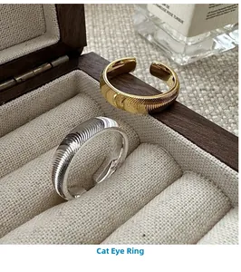 Detail view of adjustable gold and silver cat eye rings on a beige velvet jewelry tray