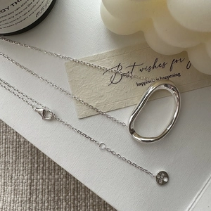 Minimalist S925 sterling silver irregular oval pendant necklace on a textured white surface