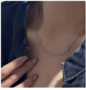 Close-up of rose gold S925 silver necklace featuring textured mesh heart pendants