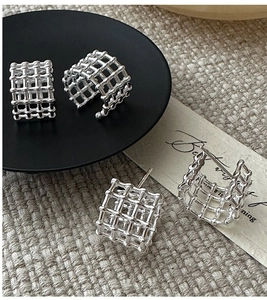 Dettaglio di orecchini minimalisti in argento S925 con design a griglia quadrata
