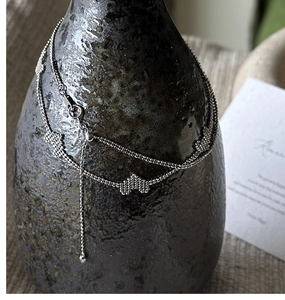 Detail view of S925 sterling silver double-layered necklace with butterfly charms on ceramic