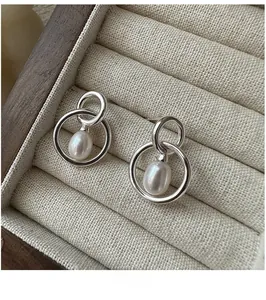 Macro shot of S925 silver double hoop earrings with water drop pearls on linen