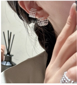 Dettaglio del ear cuff a griglia in argento e dell'anello coordinato su una modella