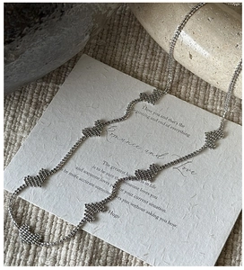 Detail of S925 sterling silver heart necklace with beaded texture on artistic paper