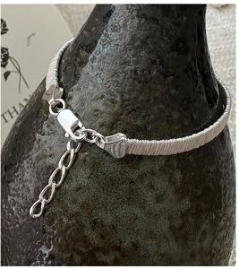 Close-up of S925 sterling silver woven bracelet with heart charm and lobster clasp