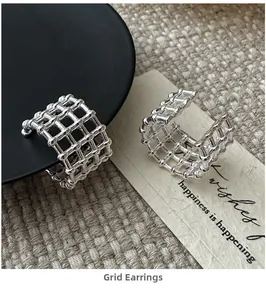 Macro shot of silver plated grid design ear clips on a stylish aesthetic background