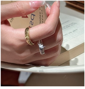 Close-up of a minimalist golden ring with textured horizontal ripples on female hand
