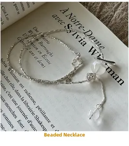 Detailed macro view of S925 sterling silver beaded necklace on vintage French book page